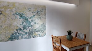 A dining area with a wooden table and chairs, a large abstract painting on the wall, and exposed brick ceiling beams. - Charming Loft in the Historic Center of Manresa. (Manresa)