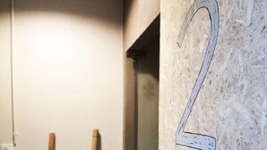 A room with a wooden ladder leaning against the wall, a whiteboard with the number 2, and a kettle on a table. - Foresttel Bkk - Hostel (Bangkok)