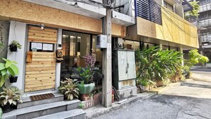 A building with a wooden facade, a visible entrance with steps, and potted plants outside. - Foresttel Bkk - Hostel (Bangkok)