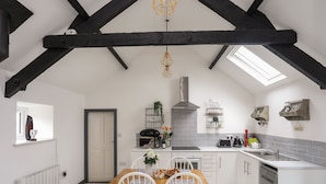 Een moderne keuken met een hoge plafond, zichtbare balken en een dakraam.