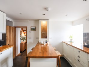 Een moderne keuken met een houten eiland, witte kasten en uitzicht op de tuin.