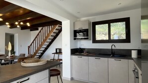 Eine moderne Küche mit einer zentralen Kochinsel, integrierten Geräten und einem Fenster über der Spüle.