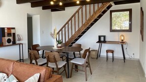 Ein geräumiger Wohnbereich mit einer Holztreppe, einem Esstisch mit Stühlen und einem Sofa.