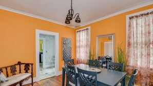 A dining room with a wooden bench, a table, and chairs. There is a door leading to another room, a painting on the wall, and a window with curtains. - Stay just 3 miles from Augusta National during Masters Week! (Augusta)