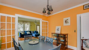 A dining area with a blue table and chairs, a chandelier, and a view into a living room with a blue sofa. - Stay just 3 miles from Augusta National during Masters Week! (Augusta)