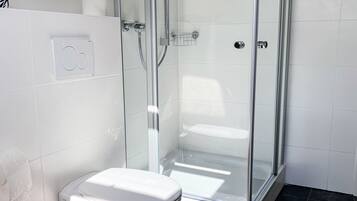 Ein Badezimmer mit einer Duschkabine, einer Toilette und einem Handtuchhalter.