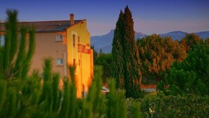 A yellow building with a sign reading "RESTAURANT" in the foreground, surrounded by greenery and mountains in the background. - Hotel Restaurant l Etape Logis (Bouc-Bel-Air)