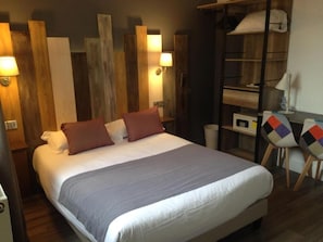 Un dormitorio con cama, almohadas, mesita de noche, lámpara, armario y silla.