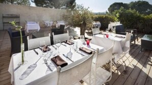 An outdoor dining area with tables set for two, surrounded by greenery and a clear sky. - Hotel Restaurant l Etape Logis (Bouc-Bel-Air)