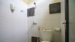 Un baño pequeño con azulejos, un inodoro, una ducha y un dispensador de jabón.