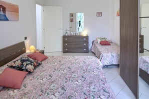 A bedroom with two beds, a dresser, a mirror, and a door leading to another room.