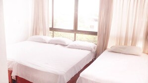 Two single beds with white linens in a room with large windows and sheer curtains. - apartamento bahía fragata  (San Andrés)