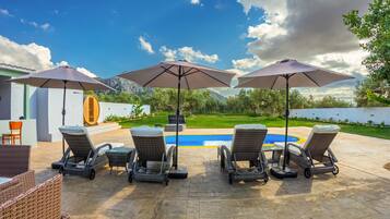 Relax by the pool surrounded by lush greenery and a majestic mountain view.