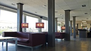 Een ruime lobby met hoge plafonds, grote ramen en moderne zithoeken.