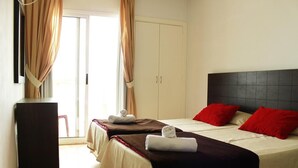 Een hotelkamer met twee bedden, een kledingkast en een bureau.