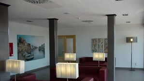Een hal met rode zitplaatsen, een groot schilderij en vloerlampen.