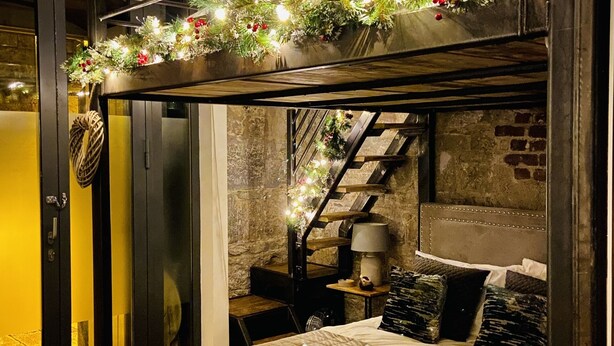 A cozy bedroom with a bed, a nightstand, a lamp, and a staircase leading to an upper level. - The Bruce @ RWY Studio - sleeps 4 guests  in 1 bedroom (Plymouth)