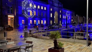 A historic building with a clock tower, illuminated by blue lights, and a plaza with outdoor seating. - The Bruce @ RWY Studio - sleeps 4 guests  in 1 bedroom (Plymouth)