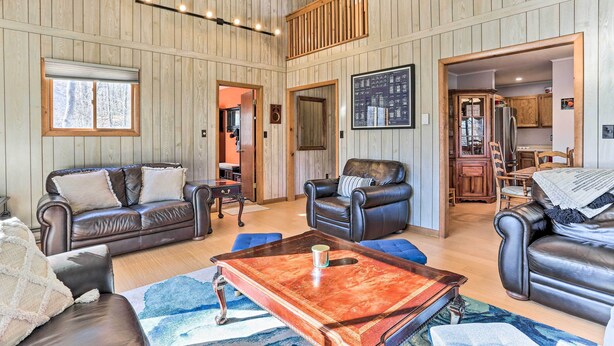 Un salón amplio con sofás de cuero, una mesa de centro y un techo de madera.