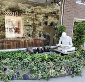 A serene outdoor seating area with a stone bench, a white sculpture, and lush greenery.
