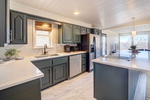 Una cucina moderna con mobili scuri, un'isola centrale e un forno a microonde integrato.