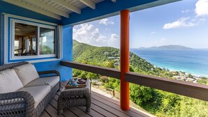 A balcony with wicker furniture, a view of the ocean, and a blue and white exterior. - Blue Moon Villa (Tortola)