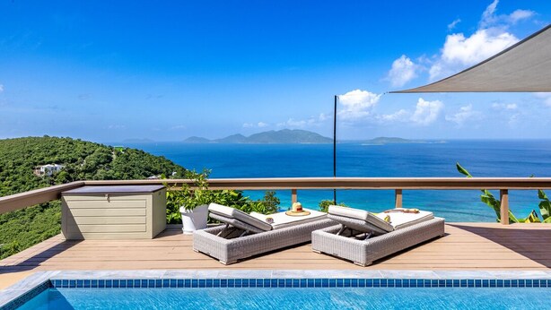 A poolside area with lounge chairs and a view of the sea. - Blue Moon Villa (Tortola)