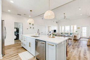 A spacious kitchen with a central island, pendant lighting, and a dining area with a view.
