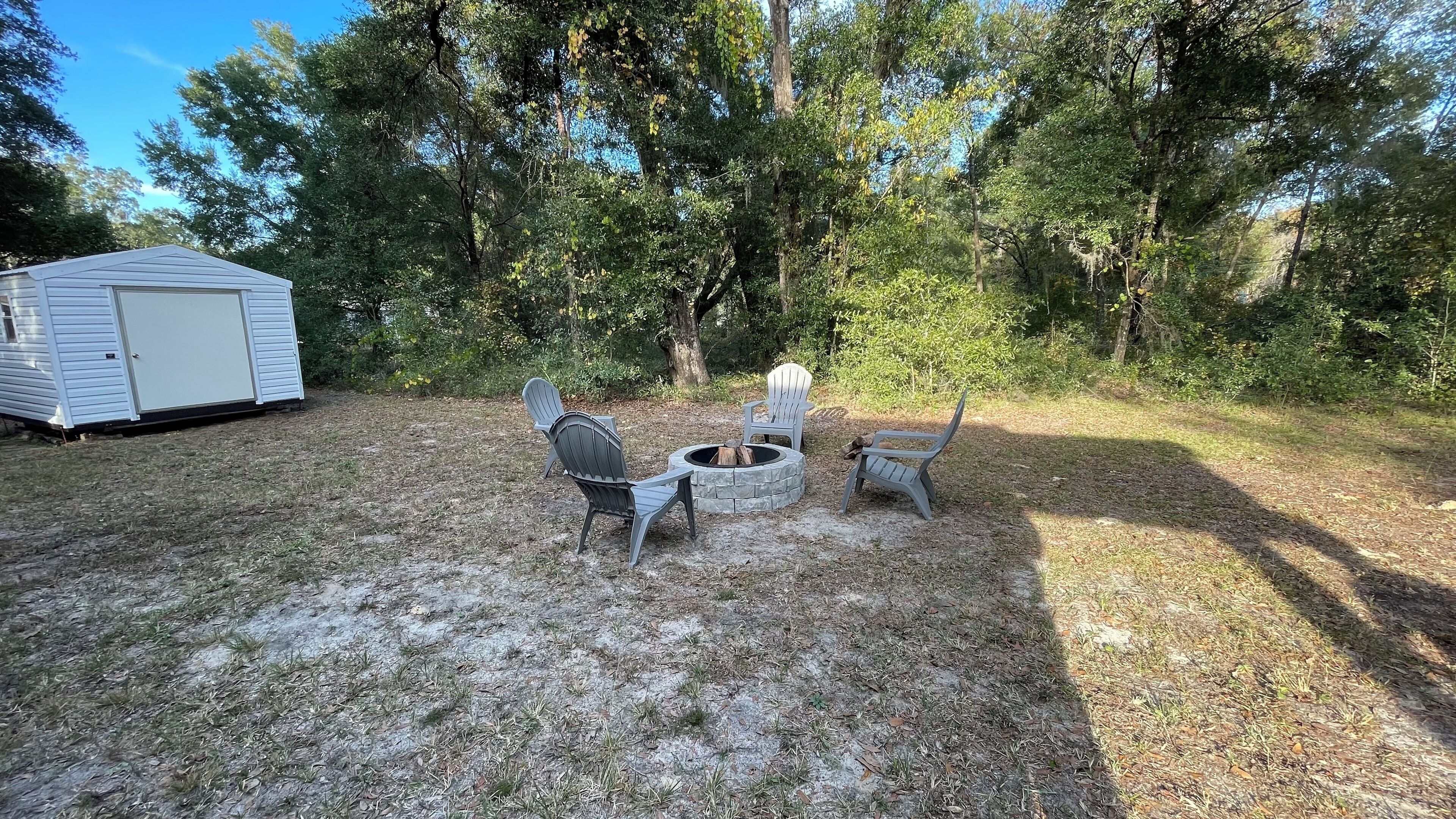 Un jardin avec un foyer et des fauteuils Adirondack.