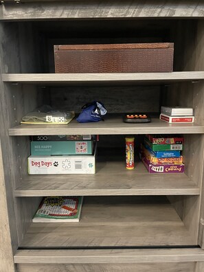 A shelf with various board games and puzzles, including 'Dog Days' and 'Jumbo Issue'.