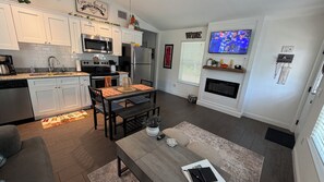 A modern kitchen with white cabinets, stainless steel appliances, and a dining area with a wooden table and chairs.