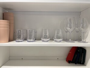 A shelf with various glassware and a red bag.