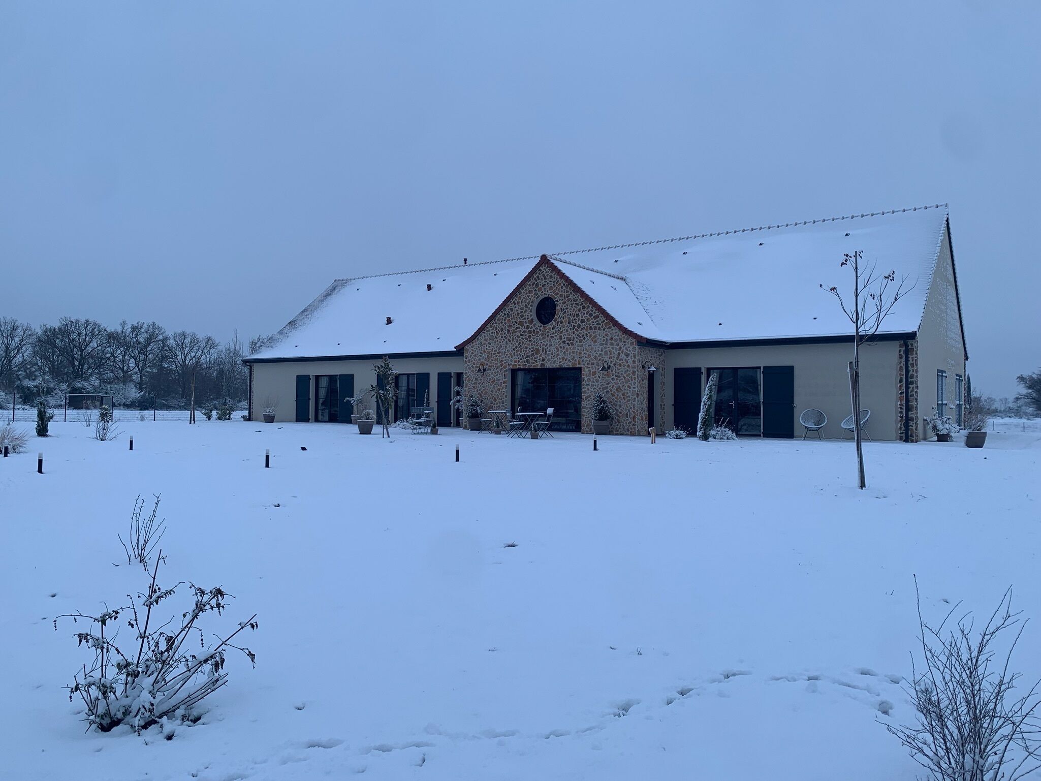 Un bâtiment en pierre, avec un toit enneigé et un grand patio ouvert.