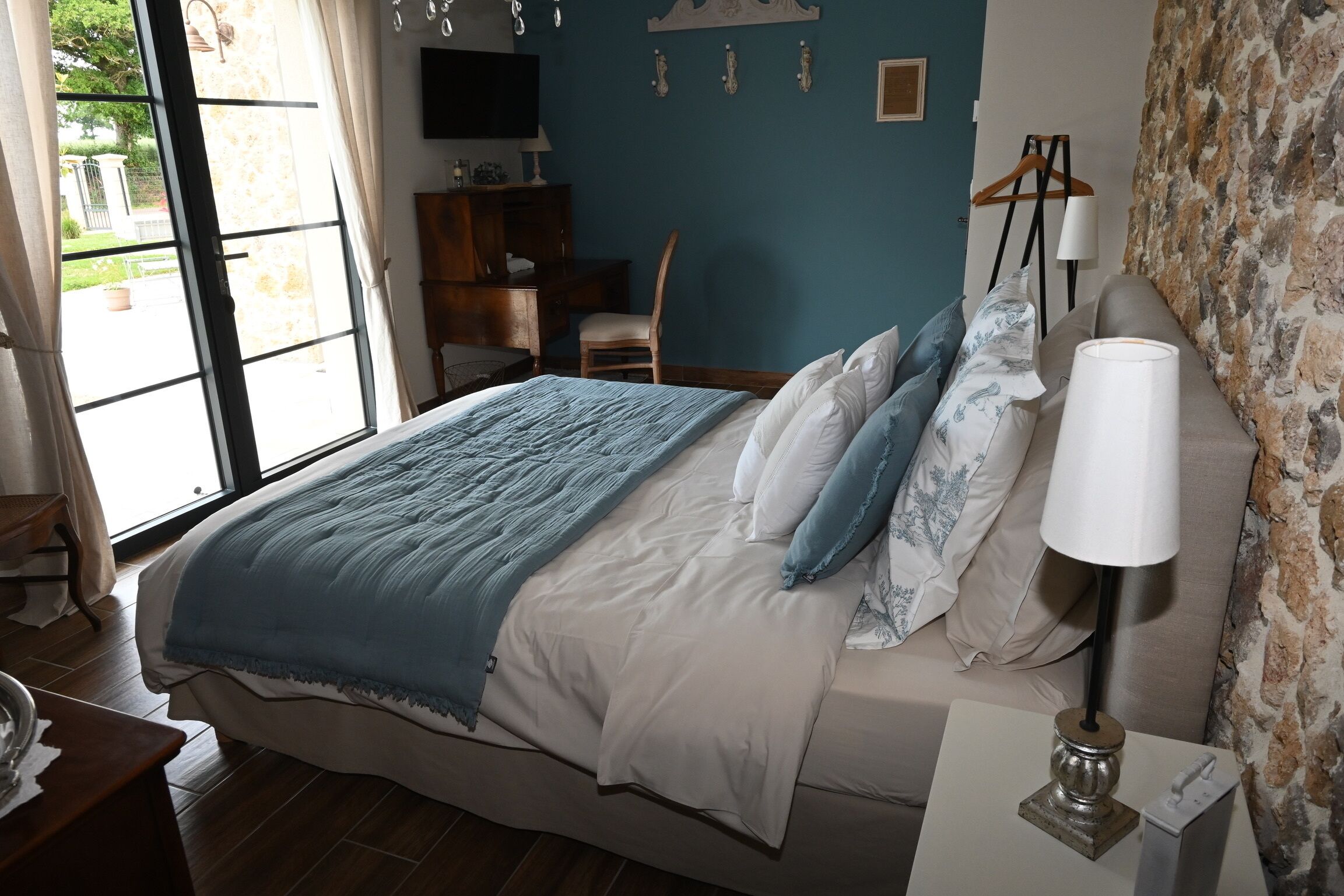 Une chambre à coucher avec un lit, une lampe de chevet, une chaise, un bureau et un téléviseur.
