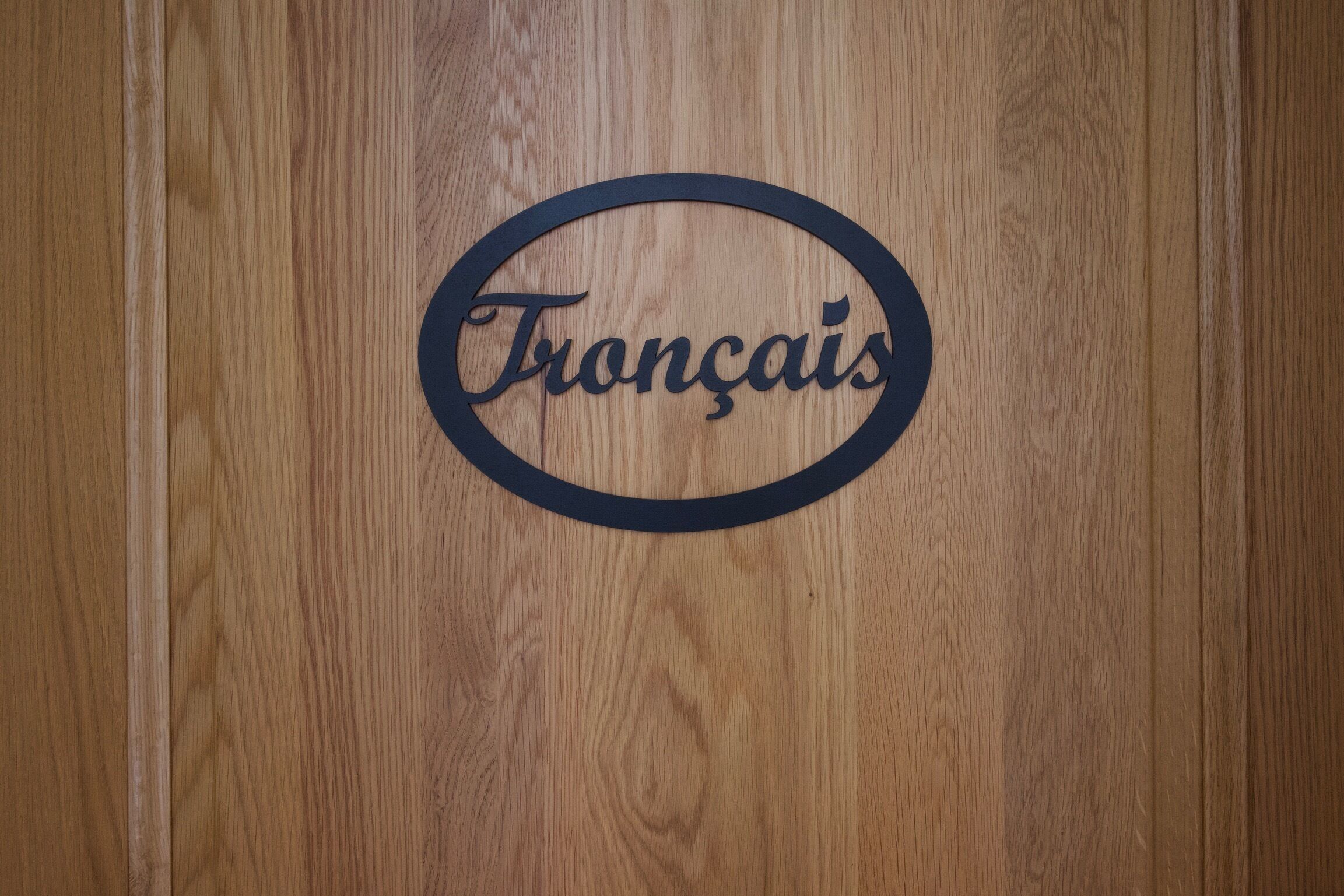 Een houten oppervlak met een rond bord waarop 'Français' staat.
