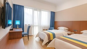 A hotel room with two beds, a desk with a lamp, a chair, and a TV. - Carrianna (Foshan)