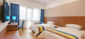 Una habitación de hotel con dos camas, un escritorio con lámpara, una silla y televisión.