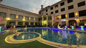 Zona de piscina de hotel con una piscina circular, un flotador salvavidas y un adorno con forma de luna creciente.