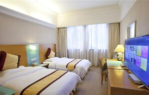 Una habitación de hotel con dos camas, un escritorio, un televisor y una ventana con cortinas.