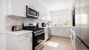 Una cocina moderna con armarios blancos, electrodomésticos de acero inoxidable y salpicadero de azulejos.