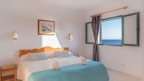 A bedroom with a bed, a nightstand, a window with curtains, and a framed picture on the wall. - Bluesea Cabo de Banos (Ciutadella de Menorca)