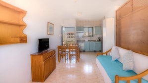 A compact living space with a kitchenette, a dining area, and a seating area with a sofa. - Bluesea Cabo de Banos (Ciutadella de Menorca)