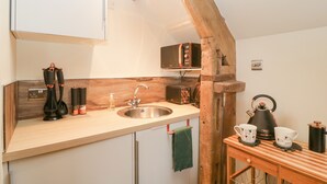 A compact kitchen with a wooden beam ceiling, a sink, a microwave, and a coffee maker. - Palace Studio (Hereford)