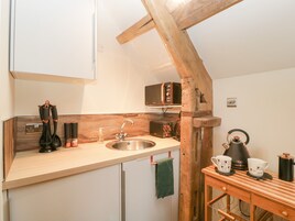 Una cocina compacta con techo de vigas de madera, un fregadero, un microondas y una cafetera.