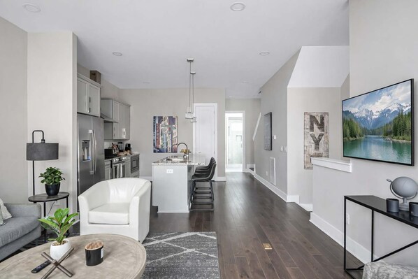 A modern living room with a sofa, coffee table, and a dining area with chairs. - Nashville Luxe Retreat • Rooftop & Hot Tub (Nashville)