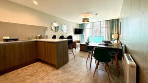 Une cuisine moderne dotée d’un îlot central, d’un coin repas avec des chaises et d’un téléviseur fixé au mur.
