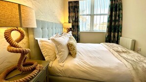 Une chambre d’hôtel avec un lit, une table de chevet, une lampe et une fenêtre avec des rideaux.