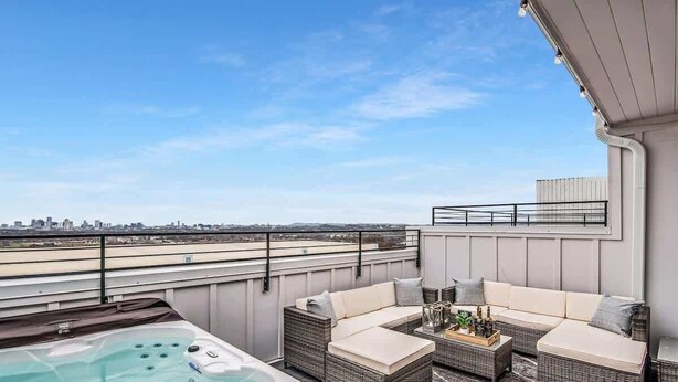 Terraço no telhado com banheira de hidromassagem, móveis de vime e vista para a cidade.