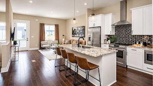 A modern kitchen with a central island, stainless steel appliances, and a black and white backsplash. - Music City Luxe Stay • Rooftop & Hot Tub (Nashville)