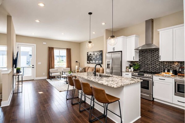 A modern kitchen with a central island, stainless steel appliances, and a black and white backsplash. - Music City Luxe Stay • Rooftop & Hot Tub (Nashville)